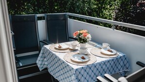 Une table dressée pour deux personnes, avec une nappe bleue à motifs, un vase de fleurs, ainsi que des assiettes contenant de la nourriture et des boissons.