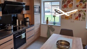 Et moderne køkken med træskabe, en sort komfur og et spiseområde med bord og stole.