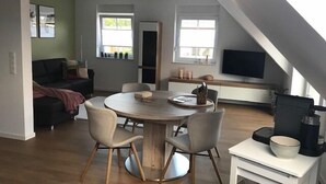 Een modern loft appartement met een eetgedeelte, een zithoek en een aan de muur bevestigde televisie.