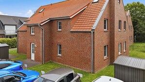 Een tweelaags bakstenen huis met schuin dak, garage en kleine tuin.