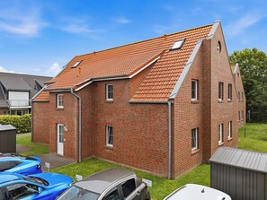 Une maison à deux étages, construite en briques, avec un toit en pente, un garage et un petit jardin.
