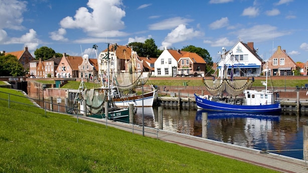 En kanal med fortøjede både, omgivet af traditionelle huse med røde tage.