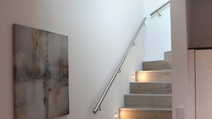 En moderne trappe med indbygget lys, et minimalistisk kunstværk på væggen og et rent, usædvanligt rum.