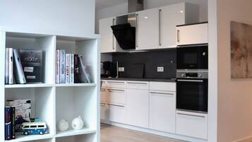 A modern kitchen with white cabinets, black appliances, and a wooden floor.