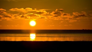 Solnedgang over et roligt hav med en klar himmel.