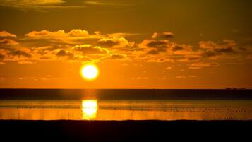 A sunset over a calm sea with a clear sky.