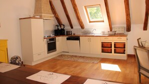 A compact kitchen with white cabinets, a wooden countertop, and a window.