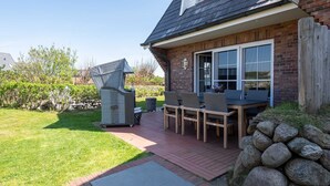 Un patio con tavolo e sedie, un barbecue e un muro in pietra.