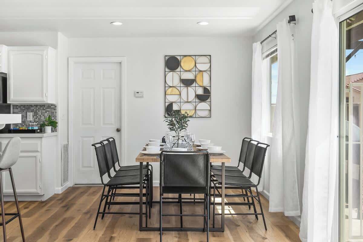 Un coin repas avec une table en bois, des chaises noires et un élément décoratif mural.