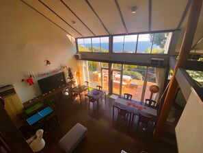 A spacious living area with a large window overlooking a patio. - COCO TERRACE -Ocean View- (Ito)