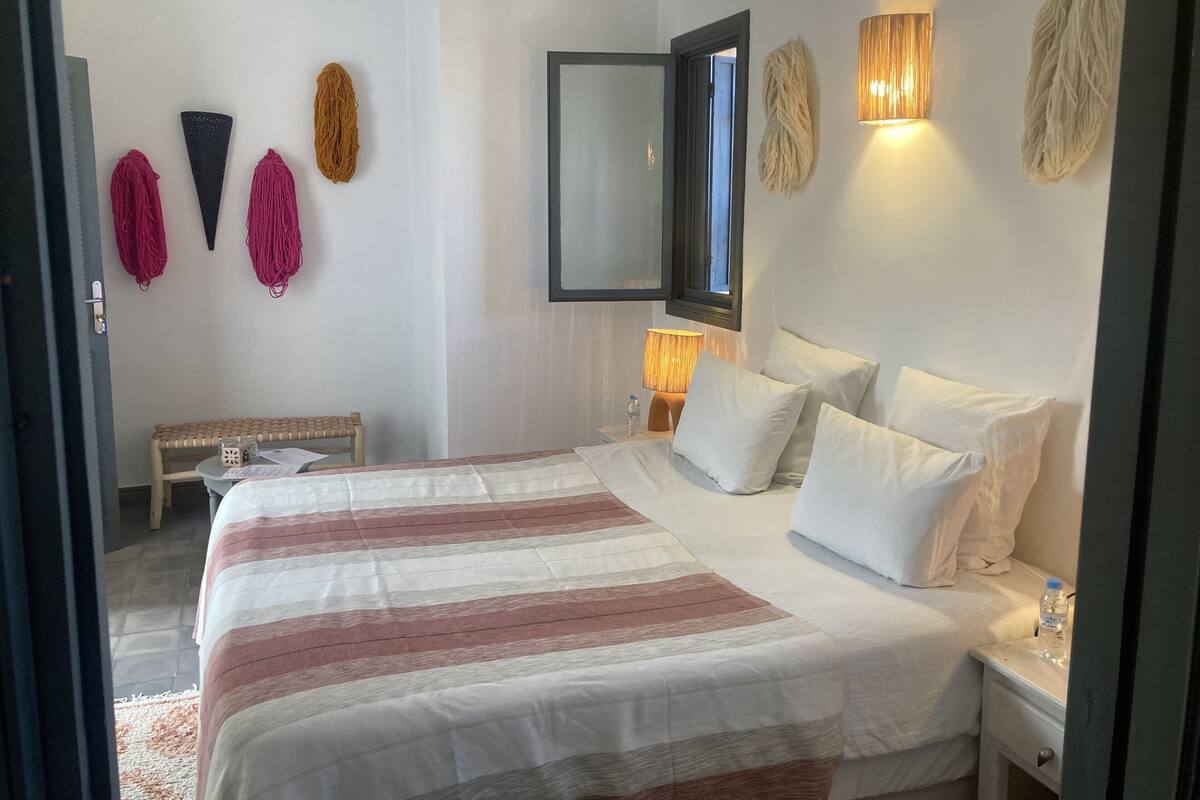 A bedroom with a large bed, bedside tables, a mirror, and wall-mounted lights.