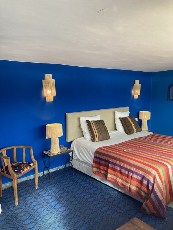 A hotel room with a large bed, two bedside lamps, a chair, and a patterned floor.