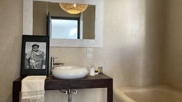 Un baño con lavamanos blanco, un espejo y una bañera.