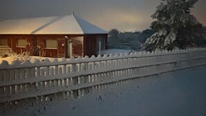 En træhytte med et sneklædt tag, omgivet af et snesikringshegn.