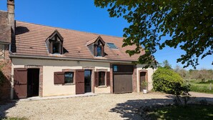Une maison à deux étages avec une allée en gravier, une cheminée et un grand portail de garage.