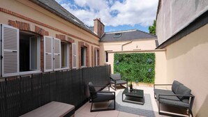 A patio with a bench, two chairs, a table, and a potted plant. - Épernay Prestige,  Apartment with terrace (Épernay)