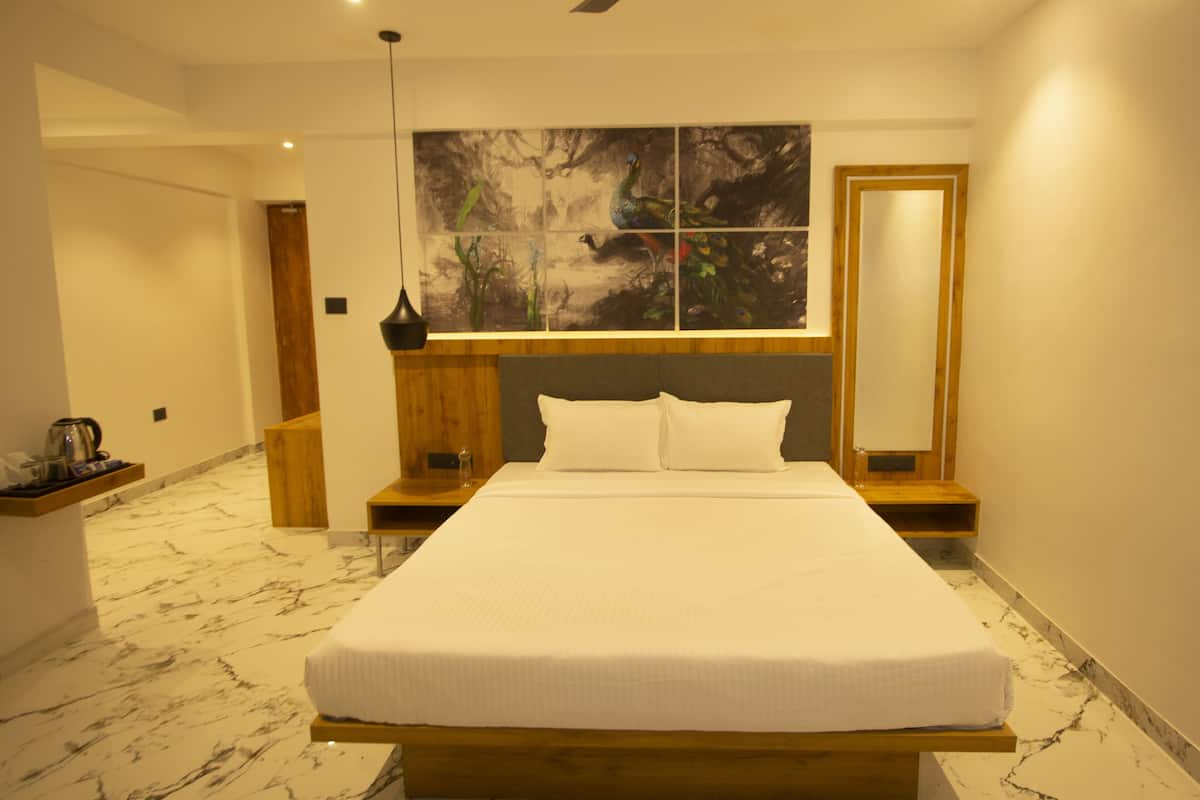 A modern hotel room with a large bed, wooden headboard, and a painting of birds on the wall.
