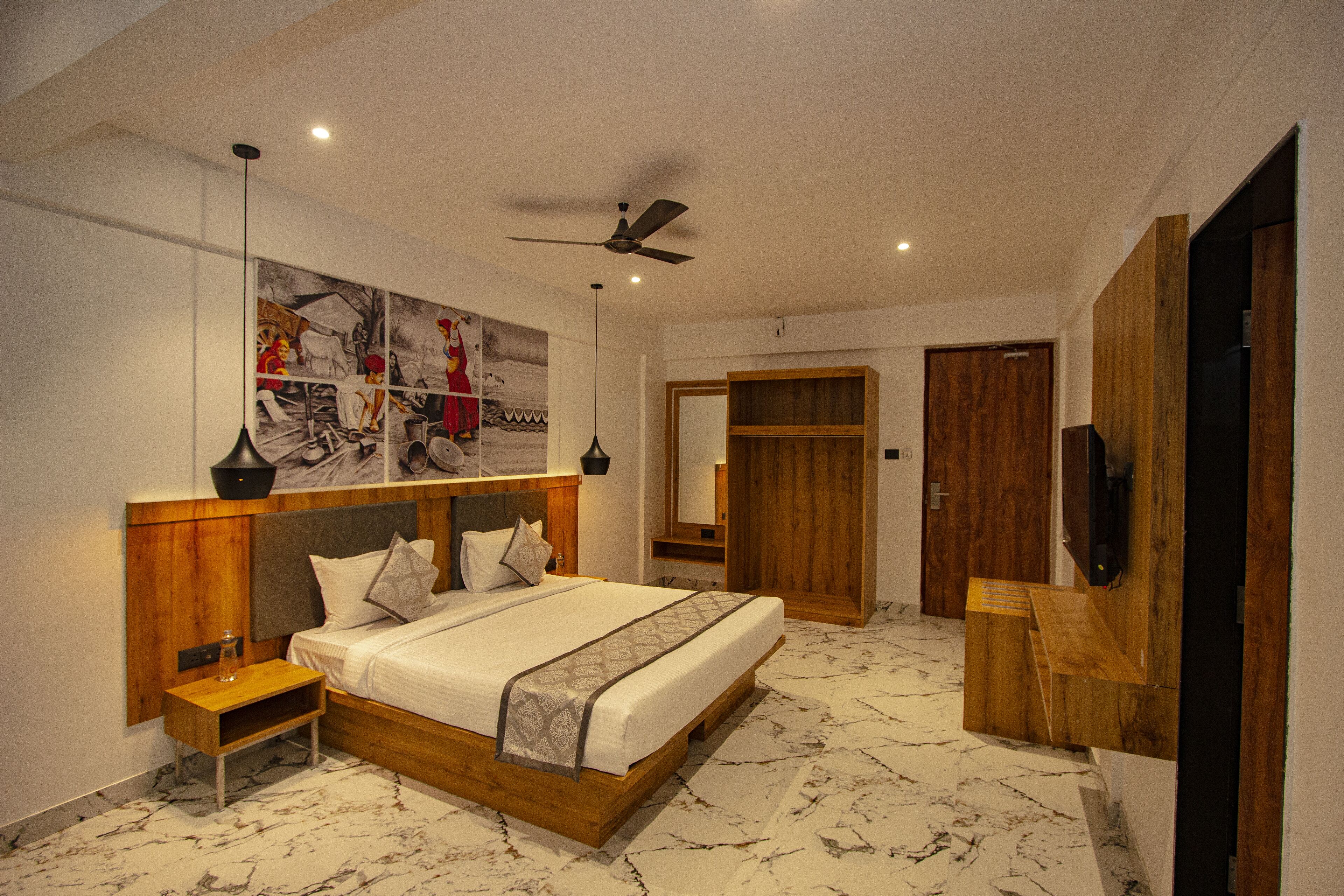 Un dormitorio moderno con una cama grande, cabecera de madera, suelo de mármol, ventilador de techo y un armario de madera.