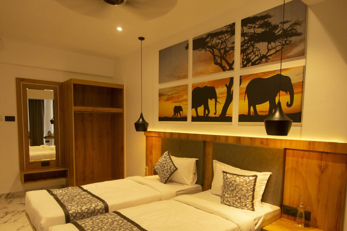 A hotel room with a large bed, a wardrobe, a nightstand, and artwork on the wall.