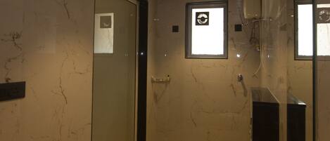 A modern bathroom with a wooden ceiling, marble walls, a glass shower enclosure, a toilet, and a sink.