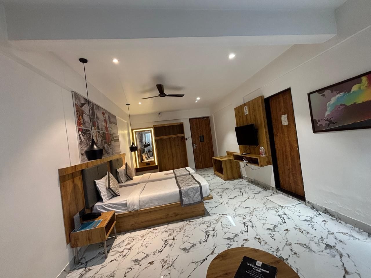 A modern bedroom with a bed, bedside tables, a ceiling fan, and a large mirror.