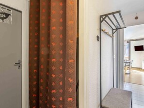Un couloir avec une porte à gauche, un rideau à motifs et une petite table à droite.