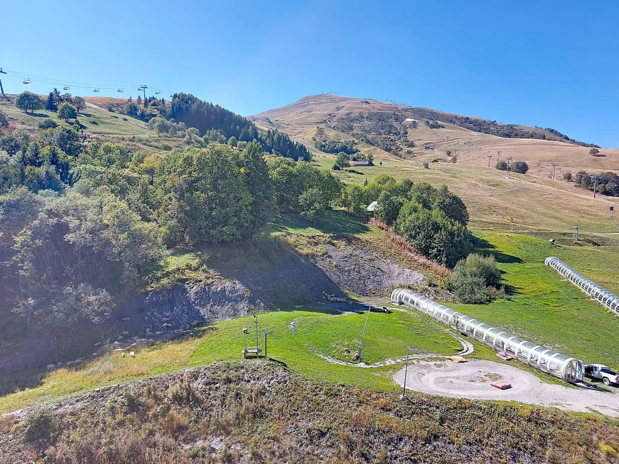 A rural landscape with a winding road, a small building, and a cable car line.