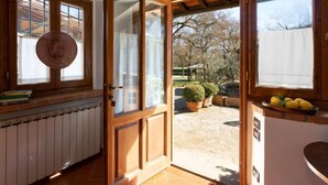 A kitchen with wooden cabinets, a radiator, and a view of the garden through a glass door. - Casa Mario by Interhome (Greve in Chianti)