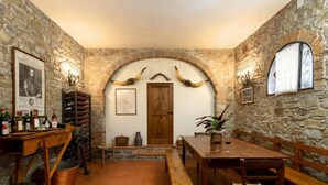 A rustic cellar with stone walls, wooden furniture, and a wine rack. - Casa Mario by Interhome (Greve in Chianti)