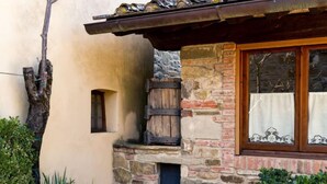 A rustic building with a stone facade, a wooden barrel, and a window with a curtain. - Casa Mario by Interhome (Greve in Chianti)