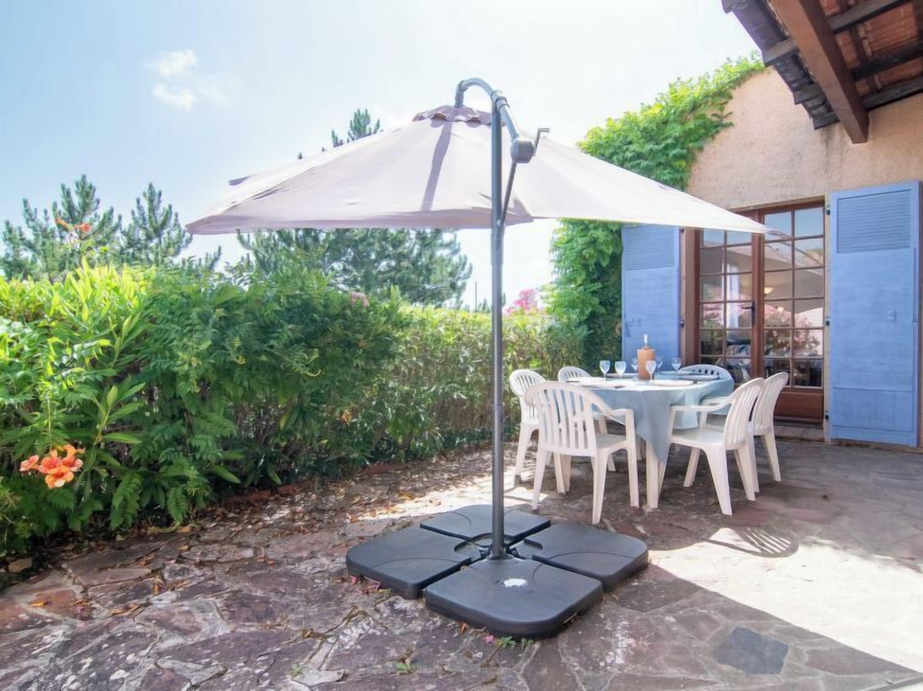 A patio with a table and chairs, an umbrella, and a stone floor.