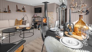 A modern living room with a sofa, coffee table, and dining area set for a meal. - Vacation home Solbu by Interhome (Eikerapen)