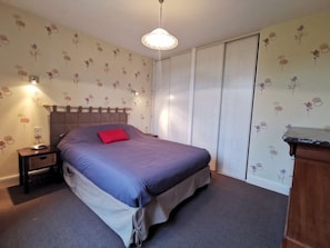 A bedroom with a bed, a nightstand, a dresser, and a wardrobe.