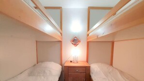 A small, narrow room with two bunk beds, a bedside table with a lamp, and a mirror on the wall. - Cozy Studio for 6 with Mountain View, Ski Locker, and Modern Amenities in Piau-Engaly (Piau-Engaly)