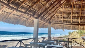 A beachside pavilion with thatched roof and wooden benches overlooking the ocean. - Hotel Paseo del Sol (La Herradura)