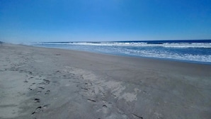 A beach with footprints in the sand and waves crashing onto the shore. - Hotel Paseo del Sol (La Herradura)