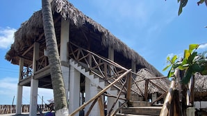 A wooden staircase leading to a thatched-roof structure with a view of the beach. - Hotel Paseo del Sol (La Herradura)