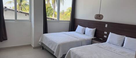 A hotel room with two beds, a large window, and a view of palm trees.