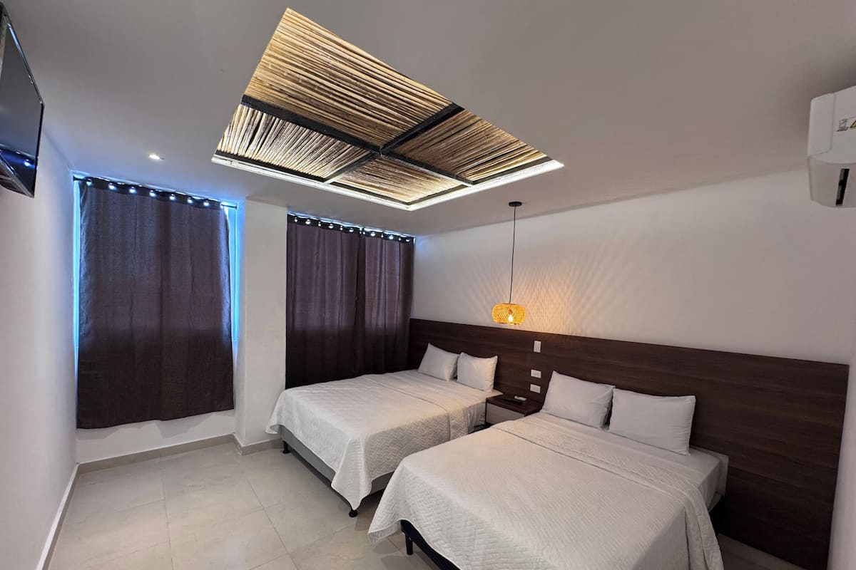 A hotel room with two beds, a modern ceiling design, and a hanging light fixture.