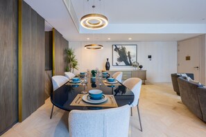 Un espace repas moderne avec une table noire, des chaises blanches et de la vaisselle bleue.