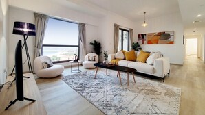 A spacious living room with a large window, a sofa set, a coffee table, and a floor lamp. - Lux 2 Bed l Stunning Sea View I Steps to JBR Beach I Sadaf 6 (Jumeirah Beach Residence)