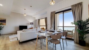 A modern living room with a dining area, large windows, and a view of the sea. - Lux 2 Bed l Stunning Sea View I Steps to JBR Beach I Sadaf 6 (Jumeirah Beach Residence)