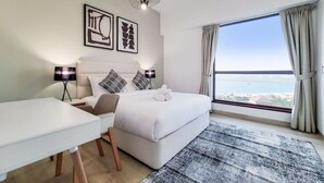 A modern hotel room with a large bed, a desk, and a view of the sea. - Lux 2 Bed l Stunning Sea View I Steps to JBR Beach I Sadaf 6 (Jumeirah Beach Residence)