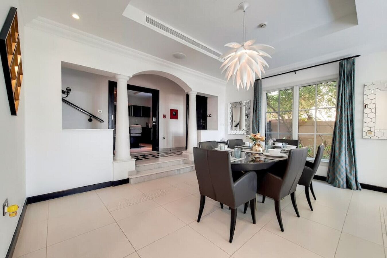 A modern dining area with a round table, dark chairs, and a pendant light.