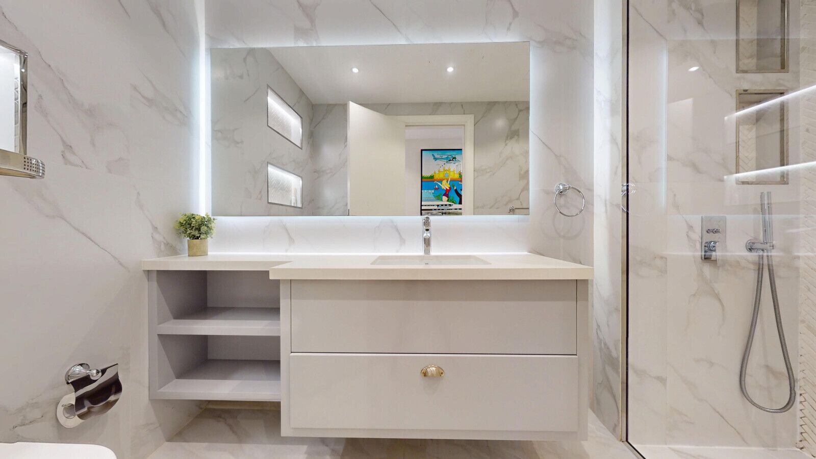 A modern bathroom with a marble wall, a large mirror, a sink with a single drawer, and a shower area.