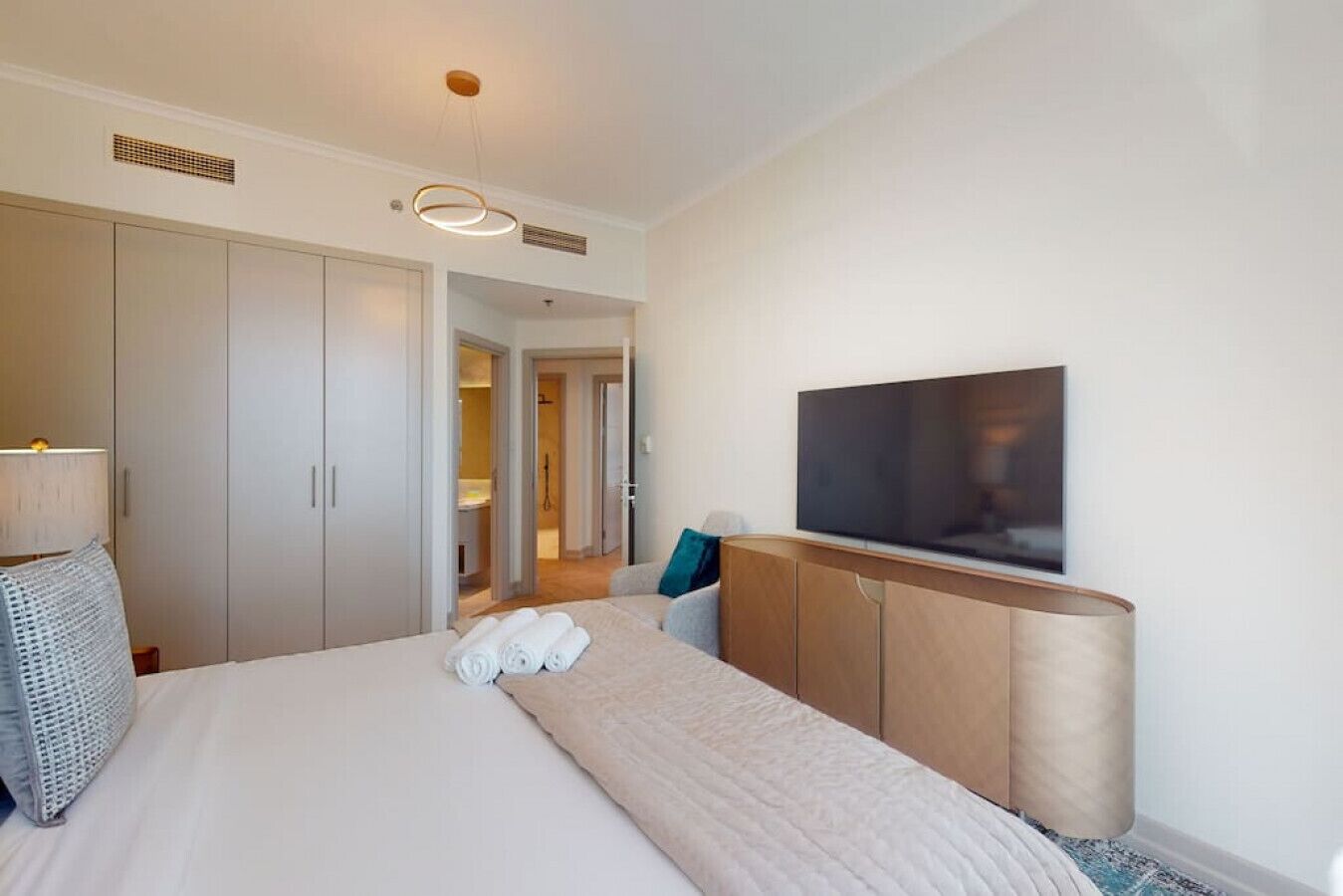 Een hotelkamer met een groot bed, een aan de muur bevestigde televisie en een kledingkast.