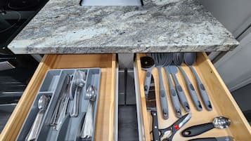 Una cucina con ripiani in granito, forno a incasso e un cassetto con utensili da cucina.