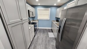 A compact kitchen with grey cabinets, a stainless steel refrigerator, and a microwave. - Paradise on Lake Harris Apt #201 (Leesburg)