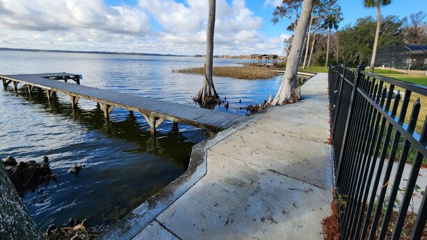 A wooden pier extending into calm water, surrounded by trees and a clear sky. - Paradise on Lake Harris Apt #201 (Leesburg)