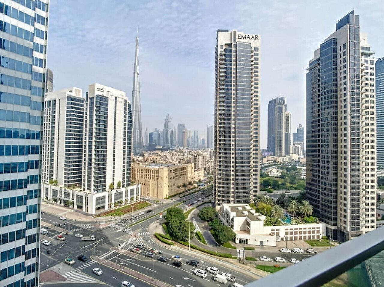Un paysage urbain avec des immeubles modernes de grande hauteur, dont une tour imposante portant l’inscription « EMAAR ».